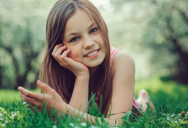 spring closeup outdoor portrait of adorable 11 years old preteen kid girl. Spending spring holidays in beautiful blooming cherry garden